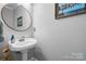 Powder room featuring a pedestal sink, round mirror, and modern lighting at 71 40Th Avenue Ne Dr # 7, Hickory, NC 28601