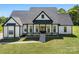 Exterior view of a charming modern farmhouse featuring white siding, black trim, and a spacious front lawn at 7419 Tesh Rd, Monroe, NC 28110