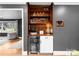 An interior view of a bar with hardwood, shelves, and a mini-fridge, with a glimpse into a bright, carpeted living room at 801 Glendora Dr, Charlotte, NC 28212