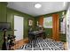 An office with green walls, a black desk, a black and white rug, and a large window at 801 Glendora Dr, Charlotte, NC 28212