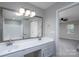 Bright bathroom featuring double sinks, a large mirror, tub and a view into the bedroom at 8125 Sheringham Way, Charlotte, NC 28227