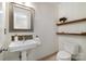 Cozy half bathroom with a pedestal sink, decorative shelves, and a framed mirror at 9500 Windygap Rd, Charlotte, NC 28278