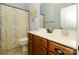 Well-lit bathroom with wood vanity, modern fixtures, a decorative mirror, and a patterned shower curtain at 1022 Bimelech Dr, Indian Trail, NC 28079