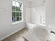 Bright bathroom featuring a tub/shower combo and a large window for natural light at 10827 Azure Valley Pl, Charlotte, NC 28269