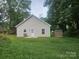 View of the backyard featuring a white door, a storage shed, and a lush green lawn at 1124 Clouse St, Gastonia, NC 28052