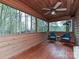 Enclosed porch with wood paneling, ceiling fan, and cozy seating with views of the surrounding woods at 119 Dills Dr, Dallas, NC 28034