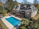 Aerial view of in-ground pool, wooden deck, backyard, and a brick home with solar panels on the roof at 124 Cedar Woods Dr, Mooresville, NC 28117