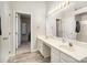 Bathroom featuring double sinks, large mirror with vanity lights, and doorway leading to walk-in closet at 14525 Arbor Ridge Dr, Charlotte, NC 28273