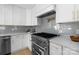 Chef's kitchen featuring a professional-grade gas range, stylish backsplash, and elegant cabinetry at 215 Wyanoke Ave, Charlotte, NC 28205