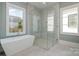 Modern bathroom showcasing a soaking tub, glass-enclosed shower, and ample natural light through two large windows at 2924 Sharon View Rd # C, Charlotte, NC 28210