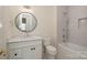 Bright bathroom featuring a round mirror, white vanity, toilet, and a tiled shower-tub combo with modern fixtures at 2924 Sharon View Rd # C, Charlotte, NC 28210