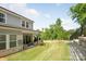 Well-manicured backyard with a covered patio, lush lawn, and stone retaining wall at 3111 Everly Enclave Way, Charlotte, NC 28210
