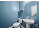 Stylish half bathroom features a pedestal sink and blue painted walls at 4006 Stockbrook Dr, Charlotte, NC 28215