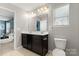 Well-lit bathroom features a double sink, dark wood cabinets, and a view into the bedroom at 4006 Stockbrook Dr, Charlotte, NC 28215