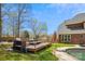 Backyard showcasing a large deck, inground pool, manicured lawn, mature trees, and brick exterior at 420 Woodlark Ct, Indian Trail, NC 28079