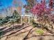 A tranquil backyard features flowering trees, mature greenery, and inviting pergola at 601 Wilmar Nw St, Concord, NC 28025