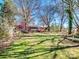 Manicured backyard with lush lawn, mature trees, plantings, and a covered porch at 601 Wilmar Nw St, Concord, NC 28025