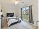 Cozy bedroom featuring a comfortable bed, neutral decor, and a large window with backyard views at 7295 Three Sisters Ln, Concord, NC 28027