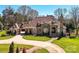 Grand, stone-clad home with a meticulously manicured lawn and circular driveway, creating an impressive curb appeal at 7295 Three Sisters Ln, Concord, NC 28027
