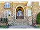 Elegant stone facade with arched entryway and wooden front door adorned with a wreath at 7295 Three Sisters Ln, Concord, NC 28027