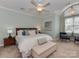 Bright bedroom featuring a large window, ceiling fan, and a plush upholstered bench at 8015 Greenview Terrace Ct, Charlotte, NC 28277