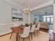 Elegant dining room with a modern chandelier, wainscoting, and view into the sunlit living room at 8015 Greenview Terrace Ct, Charlotte, NC 28277