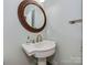 Stylish powder room features a decorative mirror, pedestal sink, and neutral color palette at 8015 Greenview Terrace Ct, Charlotte, NC 28277