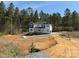 New two-story home featuring white siding, gray accents, and a wooded backdrop, in early stage of construction at 1259 Willow Grove Ln # 100, York, SC 29745