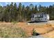 New two-story home featuring white siding, gray accents, and a wooded backdrop, in early stage of construction at 1259 Willow Grove Ln # 100, York, SC 29745