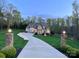 Inviting home exterior featuring a long driveway, manicured lawn, stone pillars, and warm lighting enhancing the curb appeal at dusk at 2017 Colorado Ct, Lancaster, SC 29720