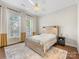 Serene bedroom featuring a wood-frame bed, neutral decor, hardwood floors, and bright natural light from large windows at 4148 Cedar Point Ave, Matthews, NC 28104