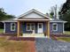 Charming home with blue siding, white trim, and a welcoming front porch featuring wood columns and a gray gravel pathway at 237 Anson Ave, Norwood, NC 28128
