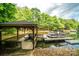 Waterfront property featuring a covered dock with a boat slip and seating area, surrounded by lush trees at 4273 Stormy Pointe Ct, Denver, NC 28037