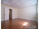 Bright, open living room with wood floors, paneled ceiling, trim work, and door to another room at 317 Belwood Dr, Belmont, NC 28012