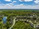 Expansive aerial view of a neighborhood with lush greenery, a serene pond, and well-maintained homes under a partly cloudy sky at 7605 Berryfield Ct, Waxhaw, NC 28173