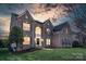 Elegant brick home with a manicured lawn, complimented by well-placed shrubbery, and charming shutters against a sunset sky at 7605 Berryfield Ct, Waxhaw, NC 28173