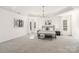 Spacious main bedroom boasts tray ceiling, chandelier, carpet floor, and natural light from windows with white curtains at 7605 Berryfield Ct, Waxhaw, NC 28173