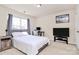 Modern bedroom with comfortable bed, side table, and a desk area with streaming monitor at 7925 Woodmere Dr, Harrisburg, NC 28075