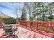 Outdoor deck featuring red railings, table and chairs with landscaping in the background at 7925 Woodmere Dr, Harrisburg, NC 28075