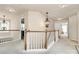 Upstairs hallway featuring ornate light fixture, white railing and multiple doorways to bedrooms at 7925 Woodmere Dr, Harrisburg, NC 28075
