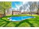 Backyard view showcasing an in-ground pool and a stone home on a lush lot with mature trees at 2116 Wilson Ave, Monroe, NC 28110