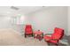 Sitting area features two red chairs with a small table, carpet, and a view of the stairs and hallway at 2116 Wilson Ave, Monroe, NC 28110