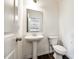 Bright powder room with pedestal sink, mirror, and wood-look floors at 558 Dulaney Dr, Fort Mill, SC 29708