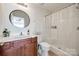 Clean bathroom featuring a shower, toilet, round mirror, sink with vanity and minimalist design at 104 S Canyon Rdg, Mount Holly, NC 28120