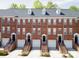 Brick townhome exteriors in a row, displaying stoops and garages beneath dormer windows and dark roofing at 1122 Dean Hall Ln, Matthews, NC 28105