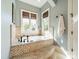 A luxurious bathroom featuring a mosaic-tiled tub with windows and travertine tile at 115 Stonewall Beach Ln, Mooresville, NC 28117