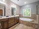 Bathroom featuring a double vanity, soaking tub, tile accents, and large window at 217 Blossom Hill Rd, Lincolnton, NC 28092