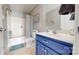 Well-lit bathroom featuring a blue vanity, a bathtub with shower, and decorative elements at 22970 Lake Tillery Rd, Albemarle, NC 28001