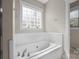 Bathroom includes white tiled tub, and a window offering natural light at 2620 Merion Hills Ct, Charlotte, NC 28269