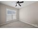 This bedroom features neutral carpeting, a window with blinds, and a ceiling fan at 2620 Merion Hills Ct, Charlotte, NC 28269